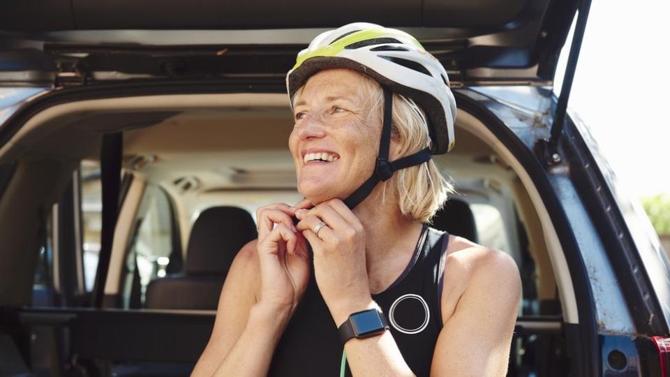 Una mujer colocándose un casco de ciclista.