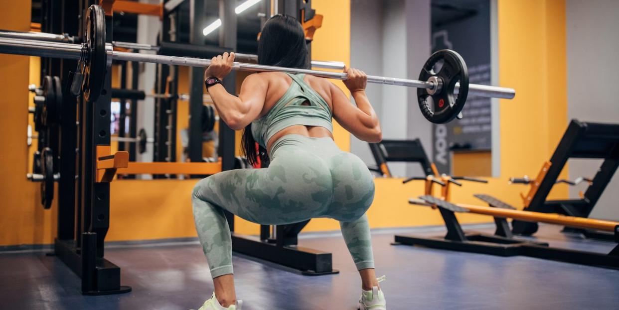 woman squatting with a weight on her back