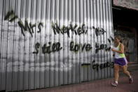 A woman jogs next to graffiti reading "Mrs Merkel we still love you, Greece" in Athens, June 27, 2015. REUTERS/Alkis Konstantinidis