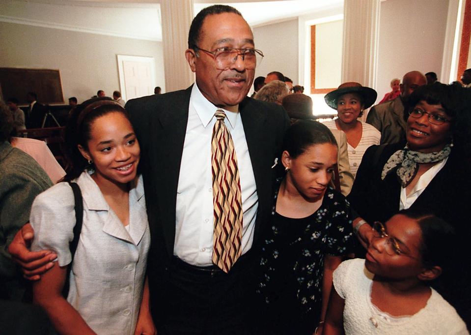 FILE - In this Aug. 2, 1999 file photo, N.C. Supreme Court Justice Henry Frye gets hugs from his granddaughters Whitney Frye, 13, left, Jordan Frye, 11, middle, and Endya,10 in Raleigh, N.C. In North Carolina's Supreme Court chamber hangs a towering painting of Chief Justice Thomas Ruffin, a 19th century slave owner and jurist who authored a notorious opinion about the “absolute” rights of slaveholders over the enslaved. Two African American chief justices have sat on the bench beneath Ruffin's stare: Frye who served as chief justice for about a year from 1999 to 2000 after 16 years as an associate justice; and Cheri Beasley, who was an associate justice for about seven years before she was appointed as chief justice in 2019. (Scott Sharpe/The News & Observer via AP)