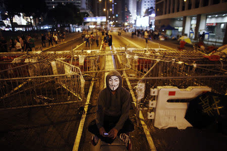 A protester sits in front of a barricade on the main street to the financial Central district, near the government headquarters building, in Hong Kong October 4, 2014. REUTERS/Carlos Barria