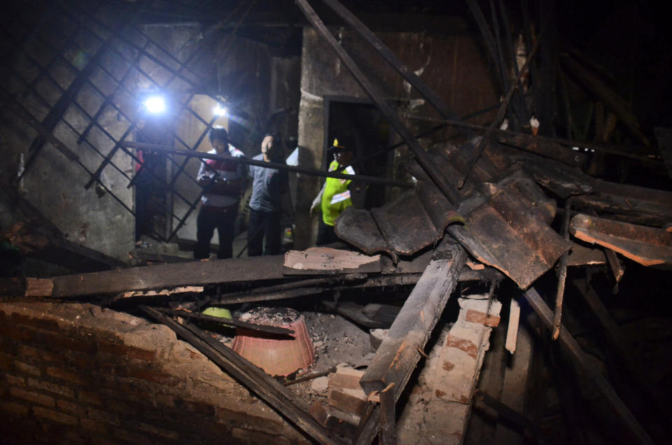 Government officials and a police officer survey a house damaged by an earthquake in Malang, East Java, Indonesia, Saturday, April 10, 2021. The strong earthquake killed a number of people and damaged more hundreds of buildings on Indonesia's main island of Java and shook the tourist hotspot of Bali, officials said Saturday. No tsunami warnings were posted. (AP Photo/Hendra Permana)