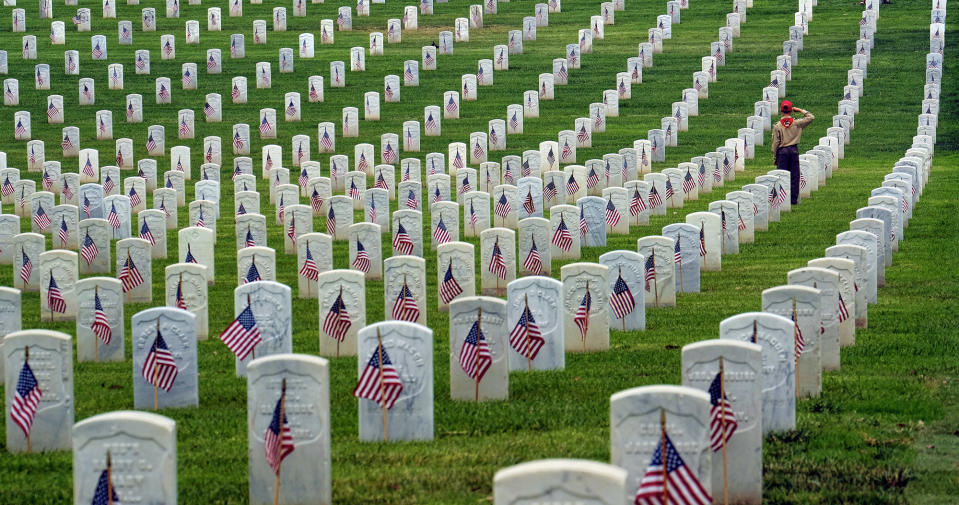 <p>A Boy Scout salutes at the foot of a grave after volunteers placed flags at the Los Angeles National Cemetery on Saturday, May 28, 2016, in preparation for Memorial Day. (AP Photo/Richard Vogel) </p>