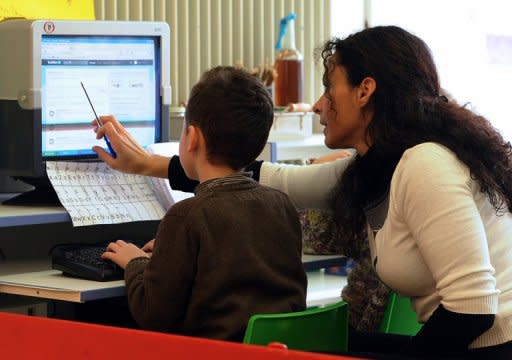 File picture shows a teacher helping a child use Twitter at a school in France. Twitter said a "cascading bug" caused outages affecting millions of users of the wildly popular site, and dismissed claims of a hacker attack