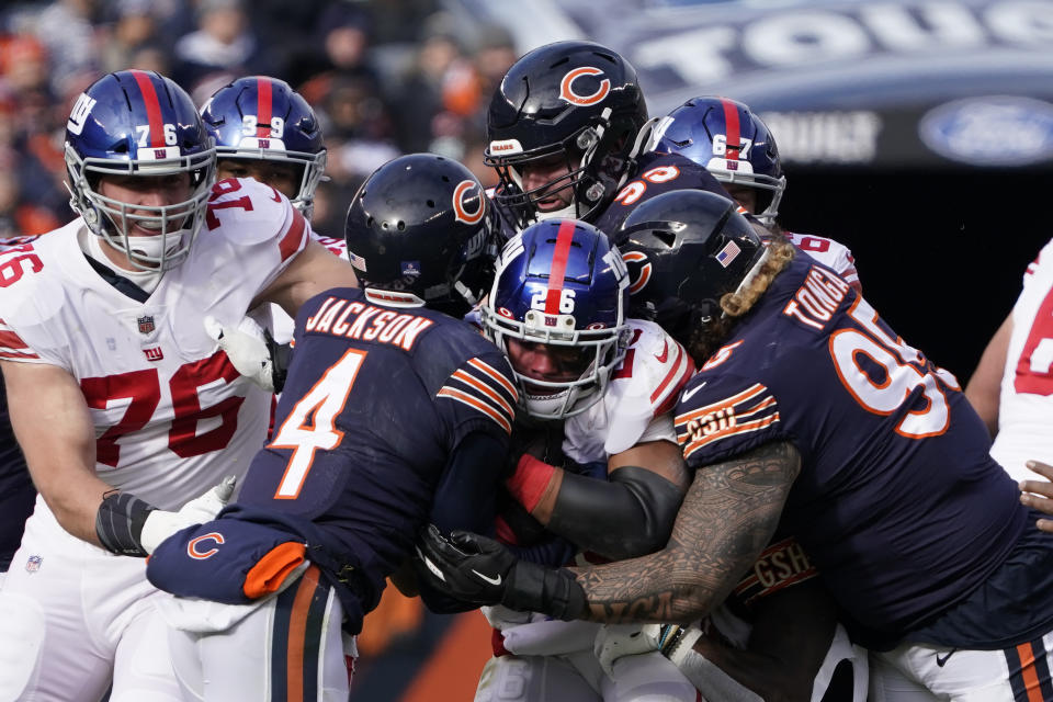 Chicago Bears free safety Eddie Jackson, left, and Khyiris Tonga (95) sandwich New York Giants running back Saquon Barkley during the first half of an NFL football game Sunday, Jan. 2, 2022, in Chicago. (AP Photo/David Banks)