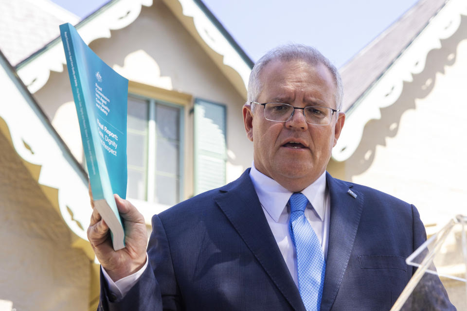 Picture of Prime Minister Scott Morrison holding up Aged Care Royal Commission final report