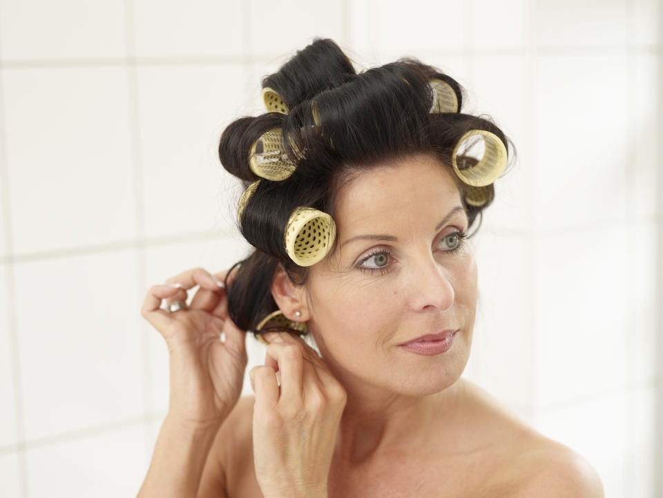 Woman with rollers in her hair, which is one way for how to prevent split ends