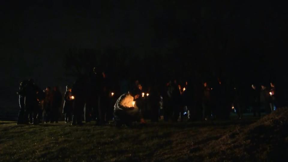 People holding candles by Rideau River near Nicolls Island on Dec. 29, 2023, where two teenage boys died earlier that week after falling through ice.