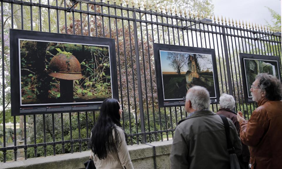 Visitors watch " Battlefield Burial Site Memorial" a picture by British photographer Michael St Maur Sheil at the Paris Luxembourg gardens, Tuesday, April 8, 2014 as part of an exhibition " Fields of Battle - Lands of Peace 14-18 ". Captured over a period of seven years, Michael’s photography combines a passion for history and landscape and presents a unique reflection on the transformation of the battlefields of the Great War into the landscape of modern Europe. (AP Photo/Christophe Ena)