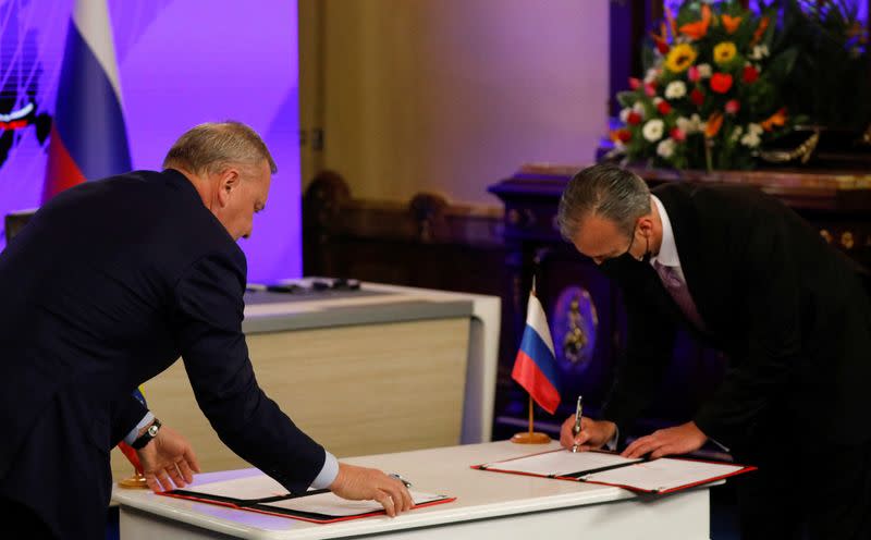 Russian Deputy Prime Minister Yuri Borisov signs documents during a bilateral agreement with Venezuela's Oil Minister Tareck El Aissami in Caracas