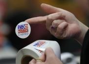 An election worker hands out stickers to voters after casting their ballots at Belmont High School on February 9, 2016 in Belmont, New Hampshire