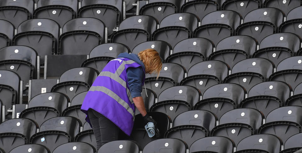 A cleaner cleans seats prior to a football game. Photo: Dave Howarth/EMPICS Sport