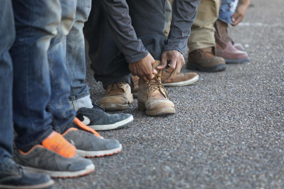 An immigrant ties his shoes after receiving his laces back from the U.S. Border Patrol before being deported into Mexico from Hidalgo, Texas, on March 14, 2017.