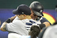 New York Yankees' Aaron Judge, right, hugs teammates after hitting a solo home run, his 62nd of the season, during the first inning in the second baseball game against the Texas Rangers in Arlington, Texas, Tuesday, Oct. 4, 2022. With the home run, Judge set the AL record for home runs in a season, passing Roger Maris. (AP Photo/LM Otero)