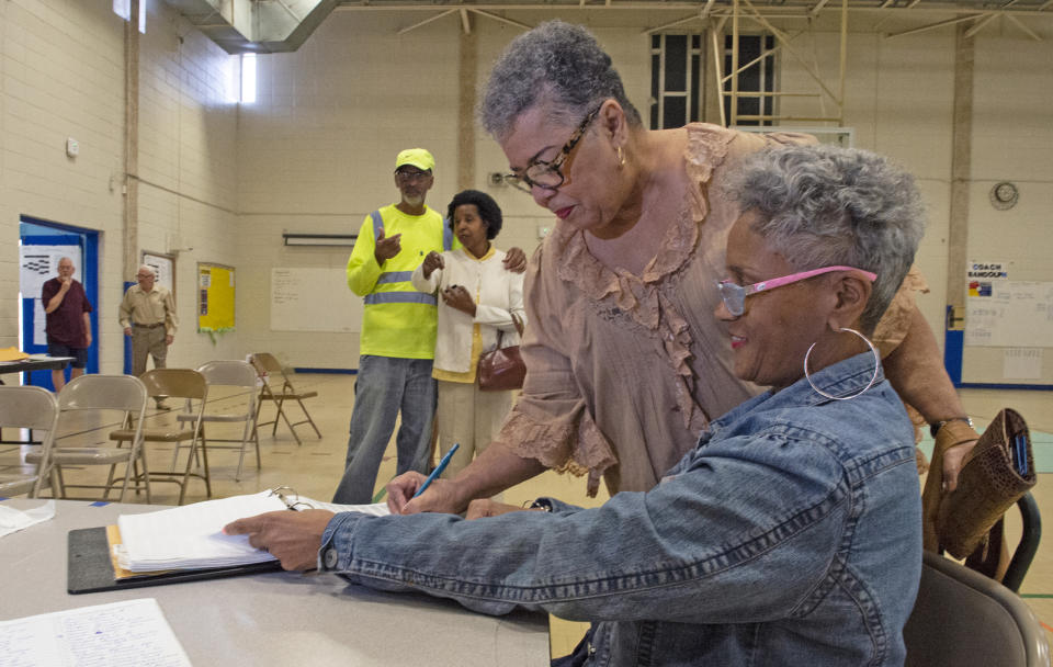 Election poll worker Annette Chambliss, right, assists Carolyn Johnson with signing the roster before voting at Sherwood Middle Academic Magnet School on Saturday, Oct. 12, 2019 in Baton Rouge, La. Gov. John Bel Edwards is fighting to hang on to a rare Democratic governorship in Deep South Trump territory, as a national GOP offensive seeks to force him into a runoff. Republicans are trying to hold Edwards under the 50% that he needs Saturday to avoid another election on Nov. 16. (Michael Dunlap/The Advocate via AP)