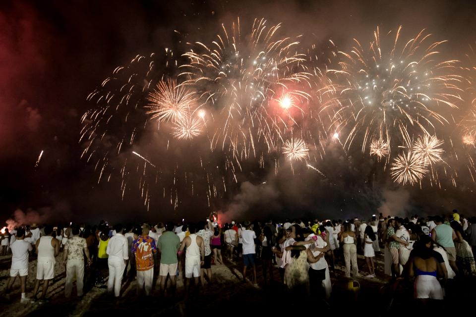 People celebrate the start of the New Year as fireworks illuminate Copacabana Beach in Rio de Janeiro, Brazil, early Monday, 1 January 2024 (AP)