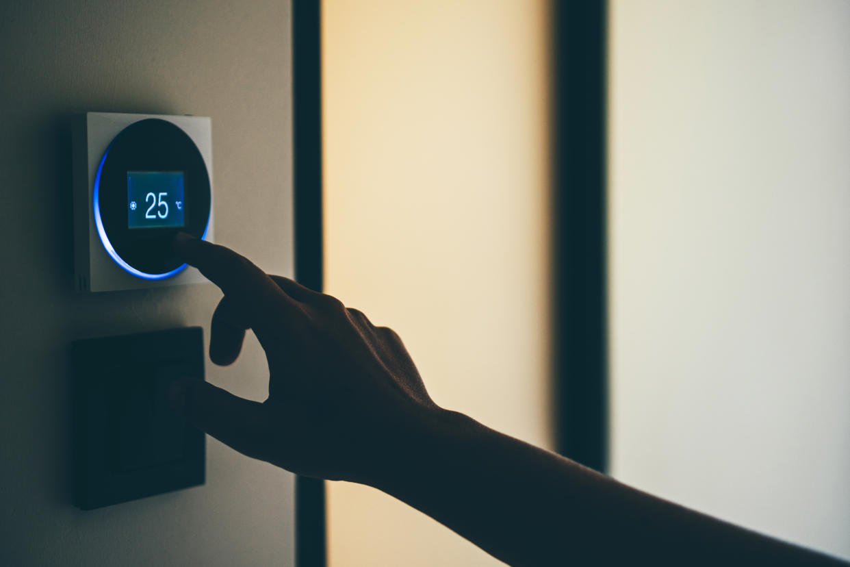 Woman Adjusts Thermostat. Woman adjusting temperature on smart thermostat at home.