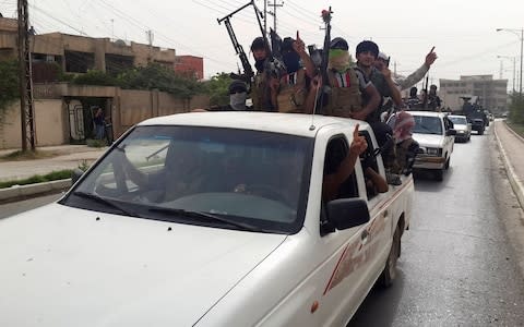 ISIL fighters celebrate on vehicles taken from Iraqi security forces in Mosul in 2014 - Credit: &nbsp;Reuters