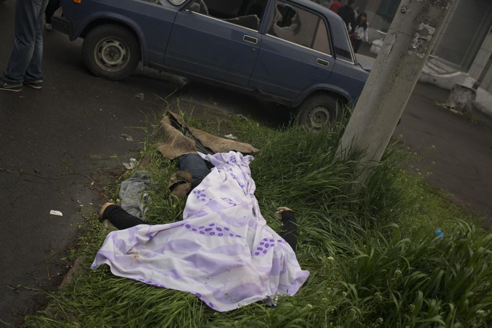 The body of a person killed during fighting between government forces and insurgents lies outside a police station in Mariupol, eastern Ukraine, Friday, May 9, 2014. Fighting exploded Friday in Mariupol, a city of 500,000 on the Sea of Azov that is on the main road between Russia proper and Crimea. The fighting between government forces and insurgents in Mariupol left several people dead. (AP Photo/Alexander Zemlianichenko)