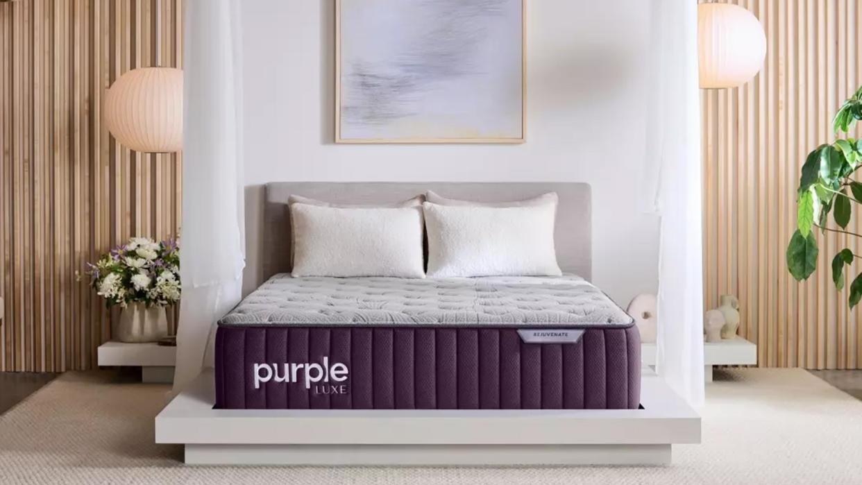  Purple Rejuvenate Mattress review image shows the bed in a luxury bedroom decorated with beautiful flowers and plants. 