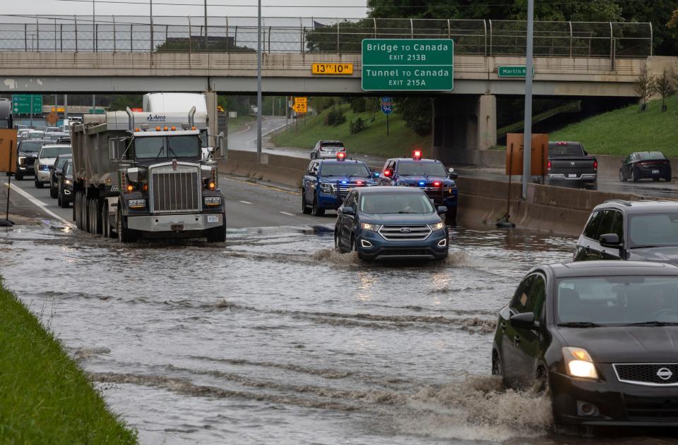 Dozens of vehicles drive through a flooded section of I-94 in Detroit on Friday, Aug. 25, 2023.