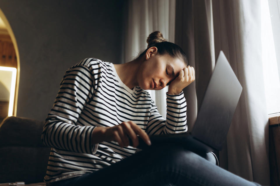 A woman looking upset and holding a laptop