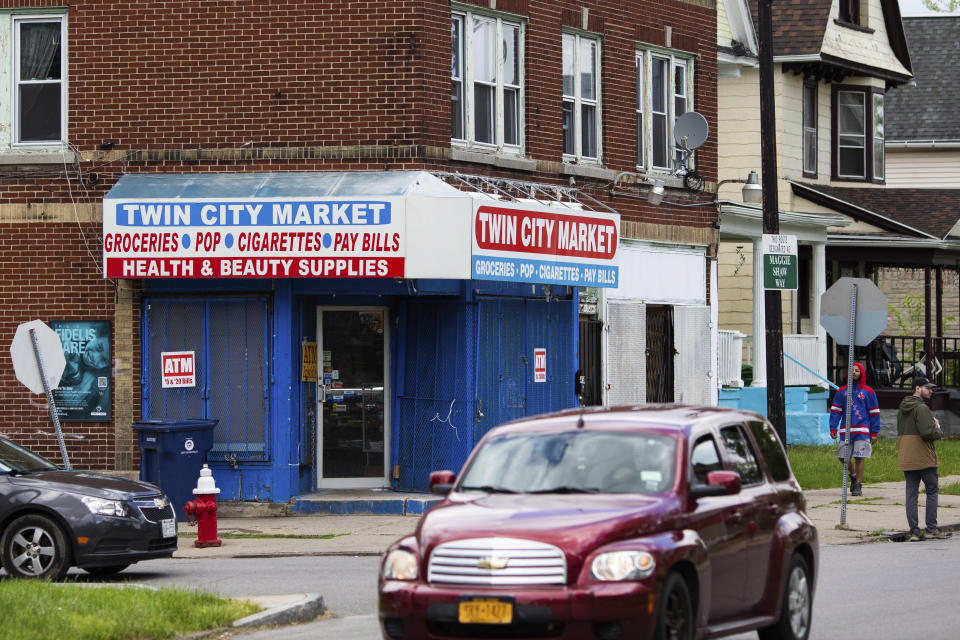 People walk and drive by Twin City Market, four blocks east of Tops Friendly Market, on Tuesday, May 17, 2022, in Buffalo, N.Y. (AP Photo/Joshua Bessex)