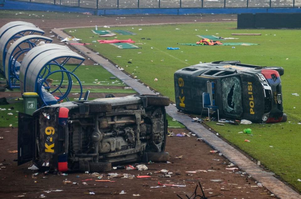 Damaged police vehicles lay on the pitch (EPA)