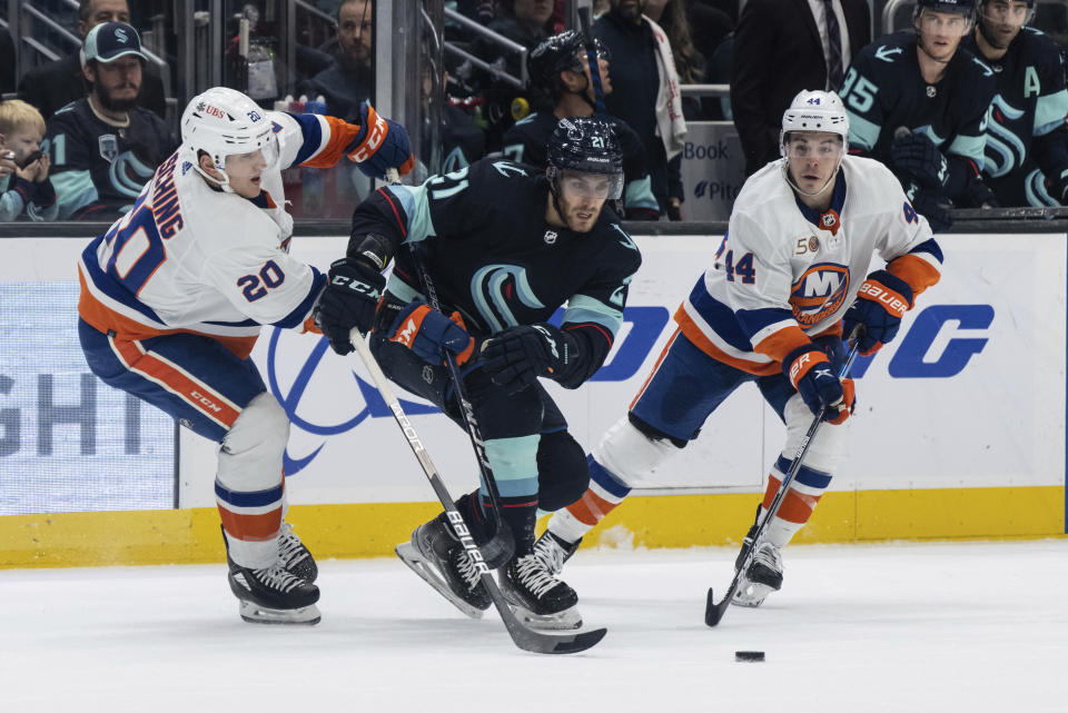 Seattle Kraken forward Alex Wennberg, center, skates against New York Islanders forward Hudson Fasching, left, and forward Jean-Gabriel Pageau during an NHL hockey game, Sunday, Jan. 1, 2023, in Seattle. (AP Photo/Stephen Brashear)