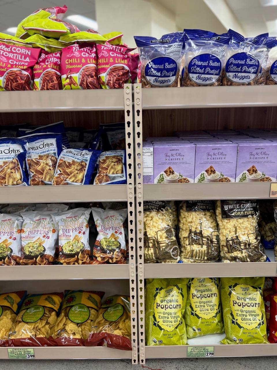 Aisle in a grocery store displaying various snack items including chips and popcorn on shelves