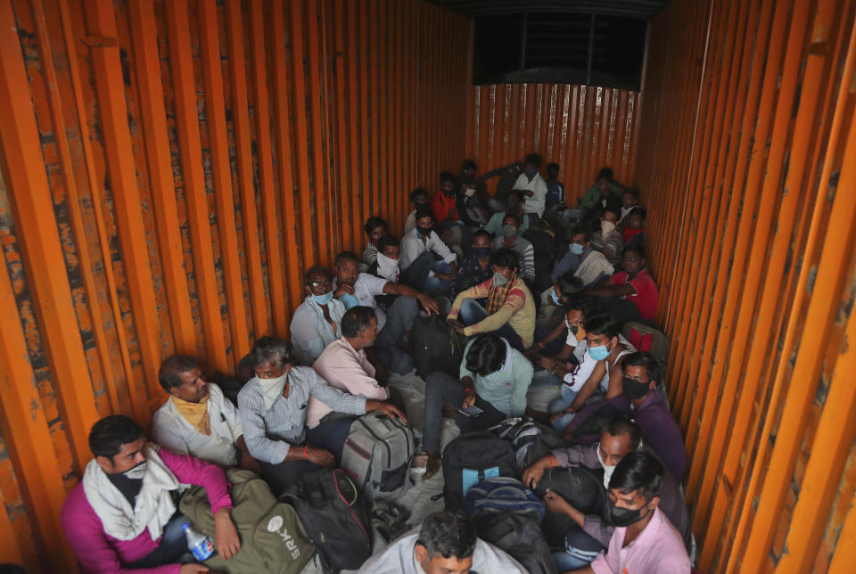 In this Tuesday, May 12, 2020, photo, migrant workers from Uttar Pradesh state sit stuffed inside a container truck hoping to return to their villages during a nationwide lockdown to curb the spread of new coronavirus on the outskirts of Hyderabad, India. Tens of thousands of impoverished migrant workers are on the move across India, walking on highways and railway tracks or riding trucks, buses and crowded trains in blazing heat amid threat to their lives from the coronavirus pandemic. (AP Photo/Mahesh Kumar A)