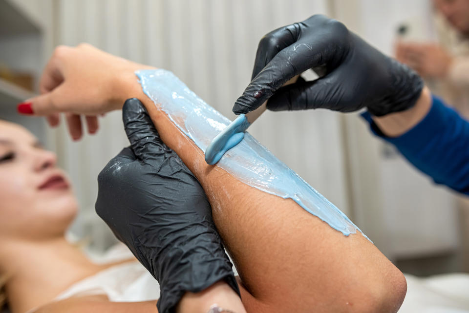 A woman having her arm waxed.