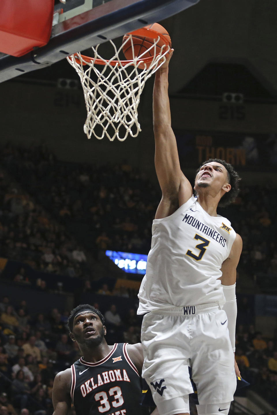 West Virginia forward Tre Mitchell (3) shoots while Oklahoma State forward Moussa Cisse (33) defends during the second half of an NCAA college basketball game on Monday, Feb. 20, 2023, in Morgantown, W.Va. (AP Photo/Kathleen Batten)