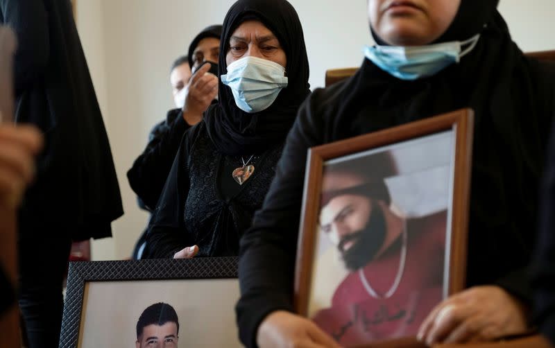 Relatives of victims of Beirut port explosion, hold their pictures during a ceremony in Beirut