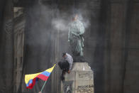 Un manifestante baja de una estatua del héroe independentista Simón Bolívar después de prender fuego a una malla protectora en su cabeza, durante una marcha contra el gobierno en la Plaza Bolívar en Bogotá, Colombia, el miércoles 12 de mayo de 2021. (AP Foto/Fernando Vergara)