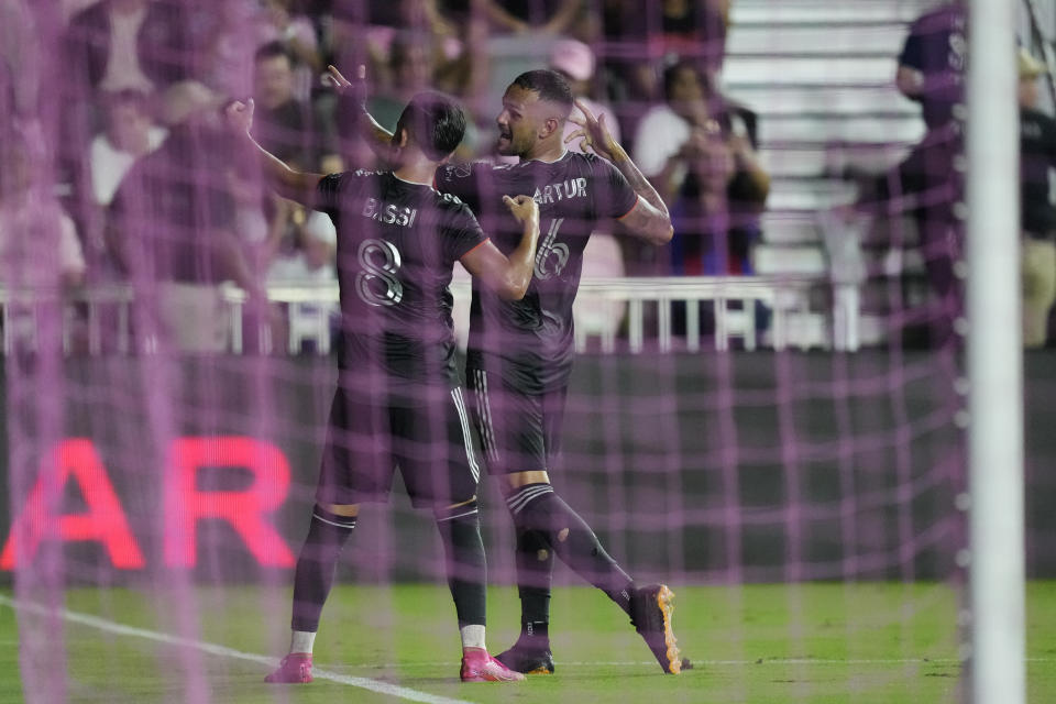 Houston Dynamo midfielders Amine Bassi (8) and Artur (6) are seen through pink goal netting as they celebrate Bassi's goal on a penalty in the first half of the U.S. Open Cup final soccer match against Inter Miami, Wednesday, Sept. 27, 2023, in Fort Lauderdale, Fla. (AP Photo/Rebecca Blackwell)