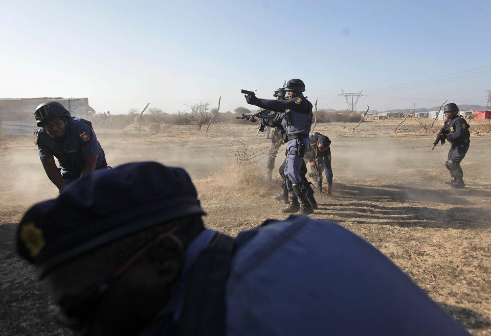Police open fire on striking miners at the Lonmin Platinum Mine near Rustenburg, South Africa, Thursday, Aug. 16, 2012. South African police opened fire Thursday on a crowd of striking workers at a platinum mine, leaving an unknown number of people injured and possibly dead. Motionless bodies lay on the ground in pools of blood. (AP Photo)