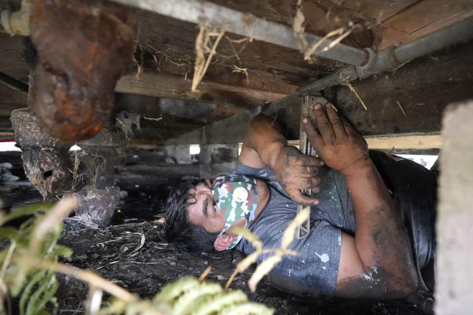 West Street Recovery's Martin Uribe works to repair busted pipes under a home, that were frozen during a recent winter storm, Thursday, Feb. 25, 2021, in Houston. West Street Recovery, a nonprofit created in the wake of Hurricane Harvey to help repair flood damaged homes, has been working since the winter storm hit to repair and replace damaged plumbing systems for residents who can't afford to do so. (AP Photo/David J. Phillip)