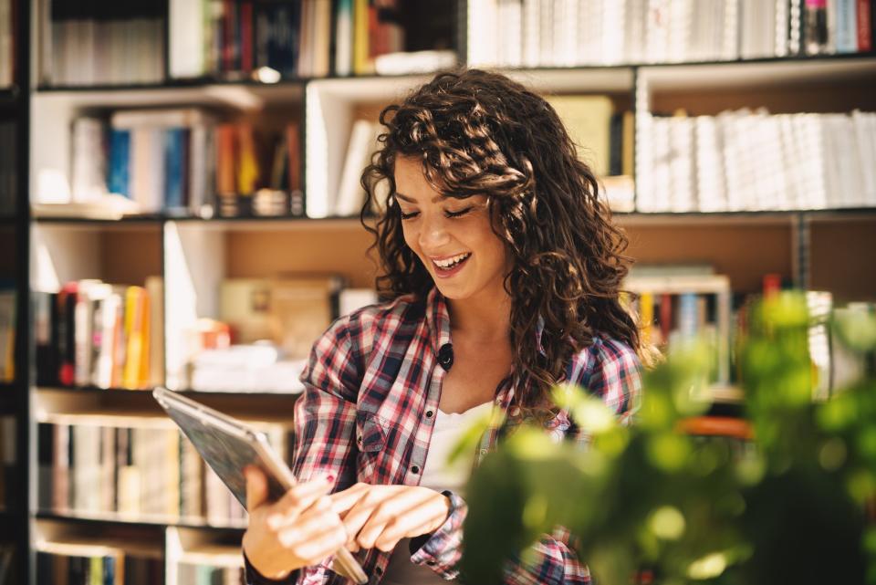 Smiling Young Woman Using Tablet In Library