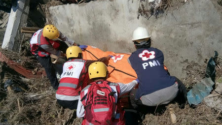 Indonesia Red Cross personnel recover a body in Palu, Indonesia September 30, 2018 in this picture obtained from social media. Picture taken September 30, 2018. PALANG MERAH INDONESIA/via REUTERS