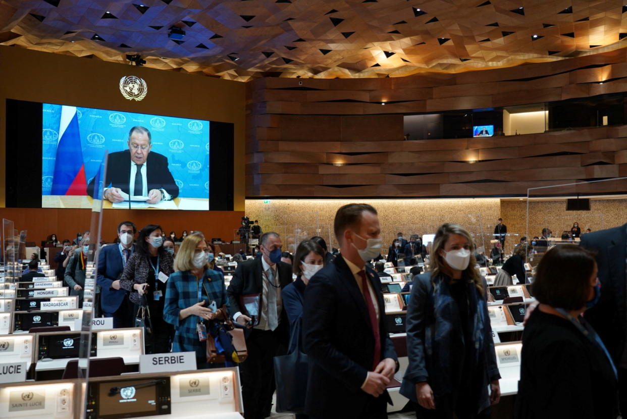 Ambassadors and diplomats walk out of the room as a prerecorded video message plays.