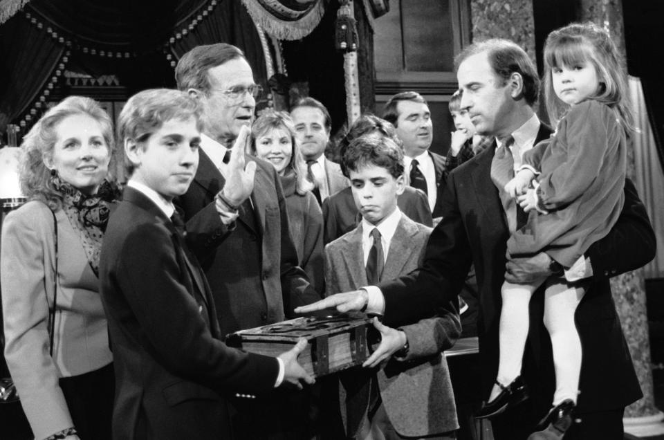 Biden holds his daughter, Ashley, while taking a mock oath of office from George H.W. Bush in 1985.