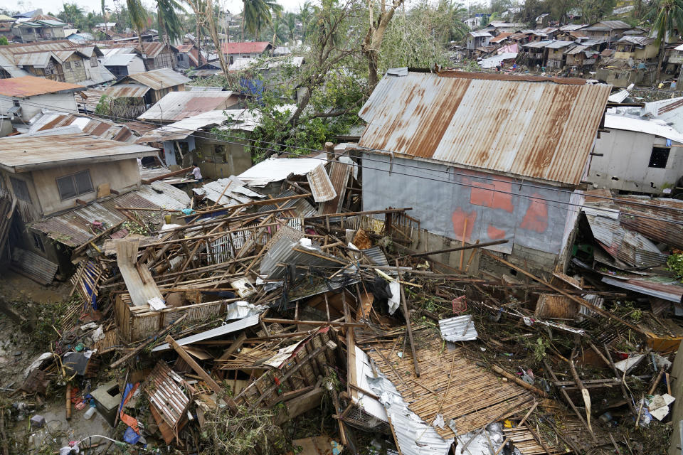 Debris is scattered over damaged homes from Typhoon Rai in Talisay, Cebu province, central Philippines on Friday, Dec. 17, 2021. A strong typhoon engulfed villages in floods that trapped residents on roofs, toppled trees and knocked out power in southern and central island provinces, where more than 300,000 villagers had fled to safety before the onslaught, officials said. (AP Photo/Jay Labra)