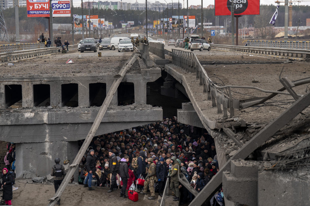 Ukrainians crowd under a destroyed bridge as they try to flee crossing the Irpin river in the outskirts of Kyiv, Ukraine, Saturday, March 5, 2022. (AP Photo/Emilio Morenatti)