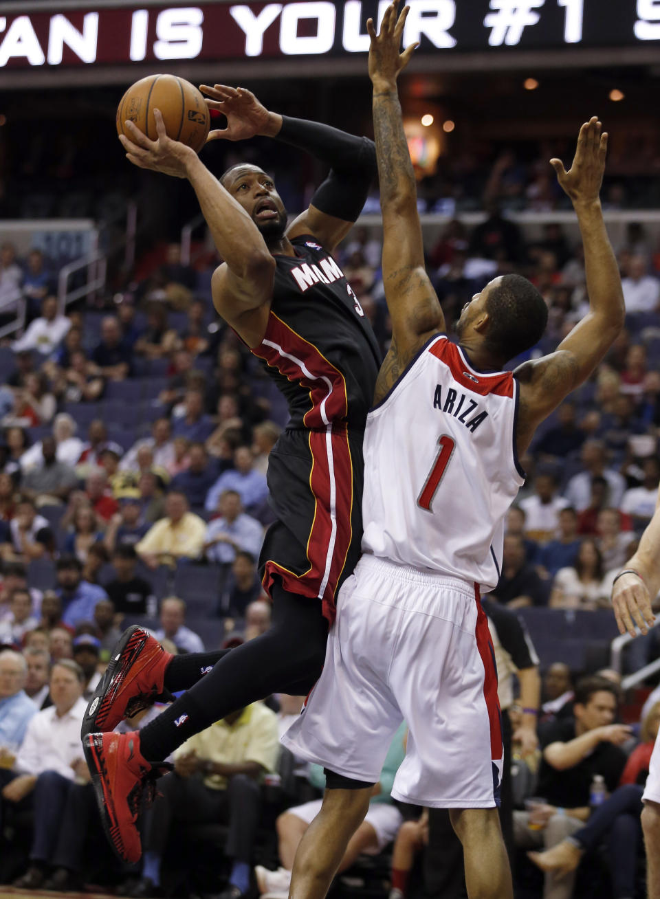 Miami Heat guard Dwyane Wade (3) shoots over Washington Wizards forward Trevor Ariza (1) in the first half of an NBA basketball game, Monday, April 14, 2014, in Washington. (AP Photo/Alex Brandon)