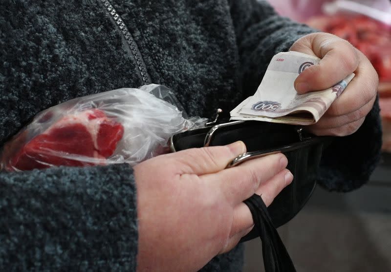A woman puts Russian rouble banknotes in a purse at a market in Omsk