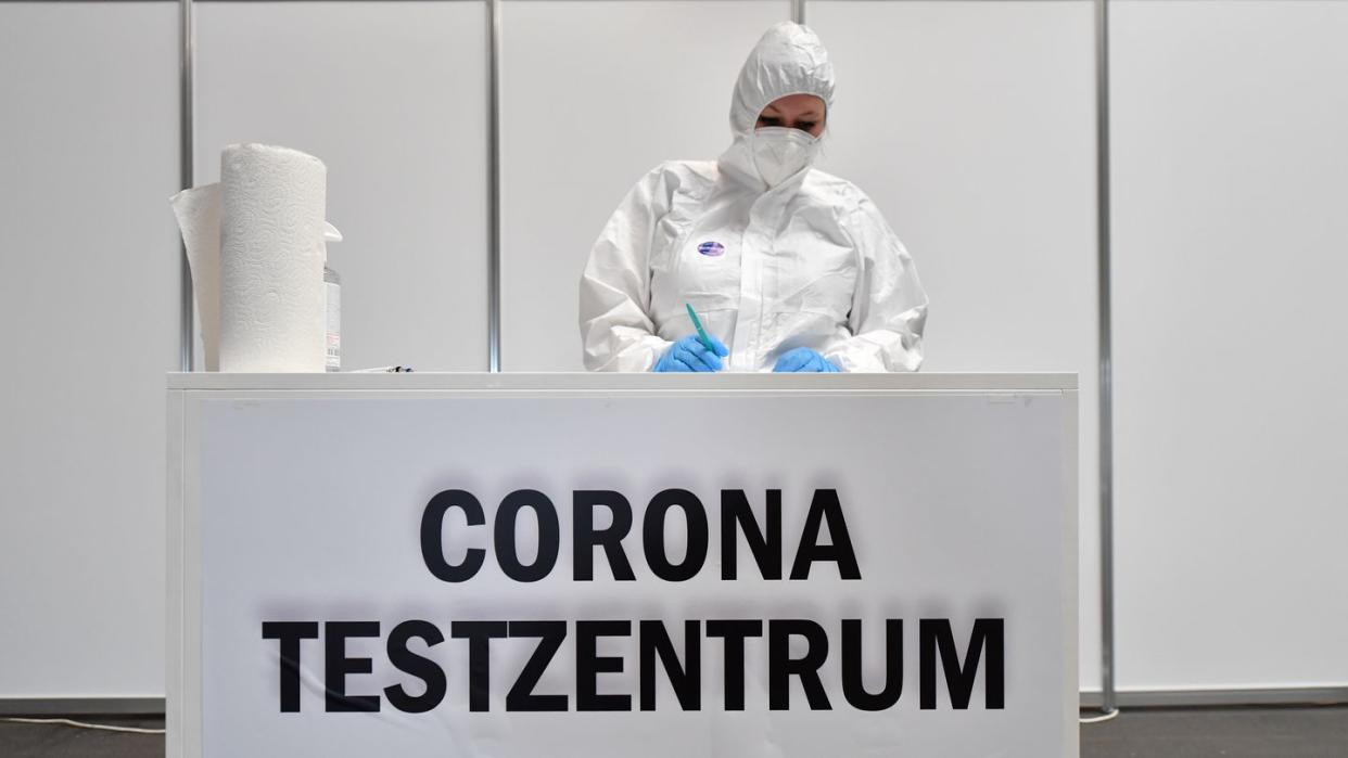 Eine Mitarbeiterin in Schutzkleidung steht im Corona-Testzentrum in der Messe Erfurt bereit.