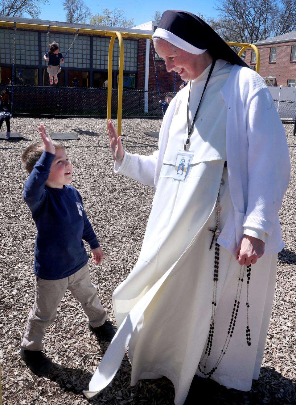 Sister Catherine Marie the Principal of Saint Rose of Lima Catholic School, gets a high-five from one of the younger students on the playground at the school, in Murfreesboro, Tenn., on Wednesday, March 29, 2023.