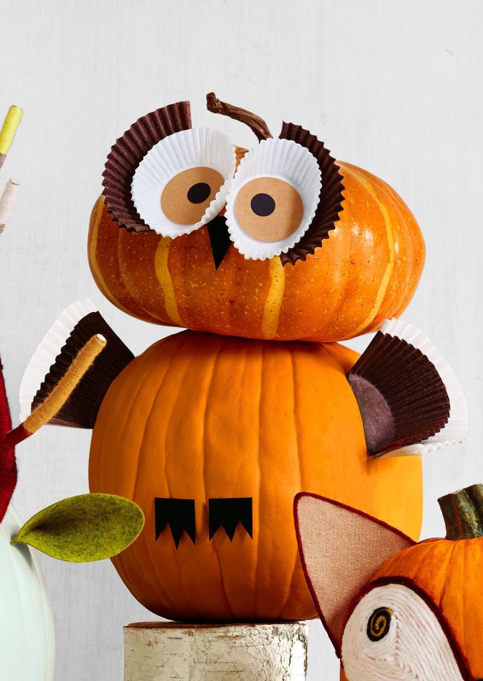 <p><em>H00</em> could resist crafting this stacked owl? <br><strong><br>Make the pumpkin:</strong> For the face, cut two circles (around the same circumference as a cupcake liner) on light brown paper and glue them to the bottom of two white liners. Cut out or draw two smaller black dots for the pupils. As for the lashes, cut a brown cupcake liner in half. Hot glue the eyes to the pumpkin.</p><p>For wings, cut a brown and a white liner in half and attach to the sides of bottom pumpkin. Cut a triangle beak and feet from black card stock and glue to the body. </p>