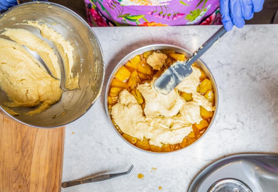 The batter is spread over the pineapple in the cake pan.